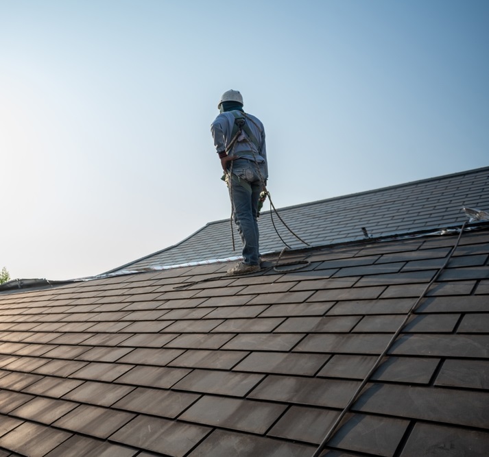 Experienced roofing contractor performing roof installation and safety-secured work on a residential shingle roof – San Marcos Roofing.