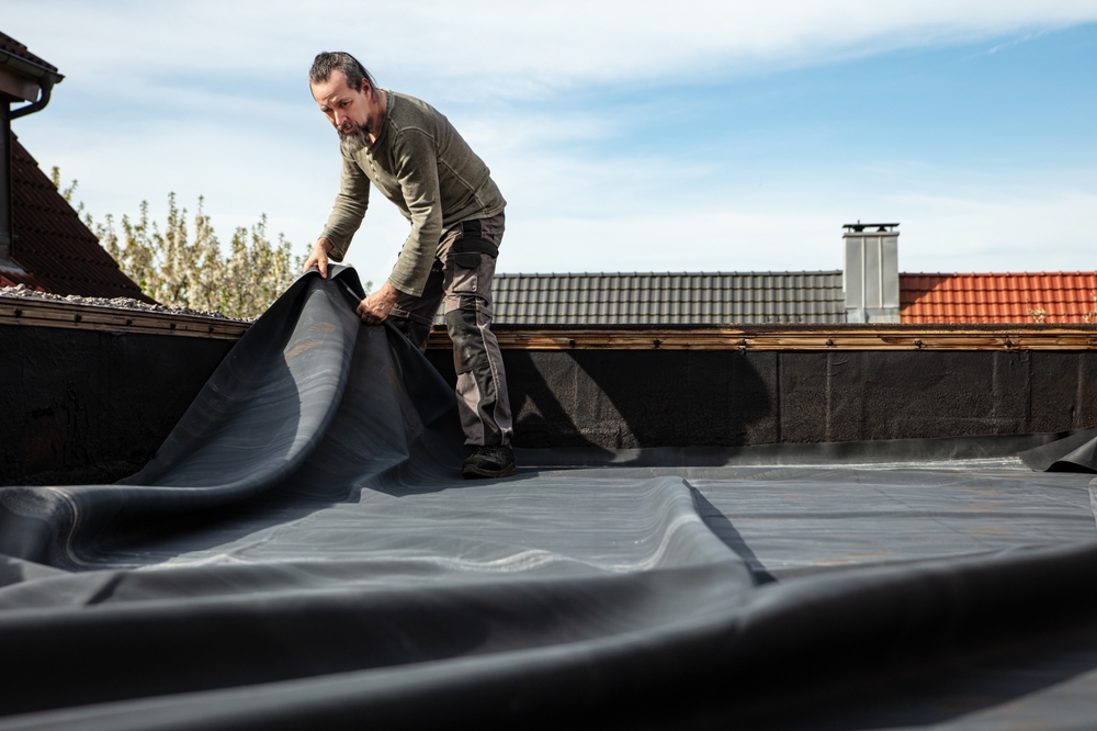 Roofer installing protective roofing underlayment as a critical base layer that improves moisture resistance and long-term roof performance - Roofing Materials in San Diego.